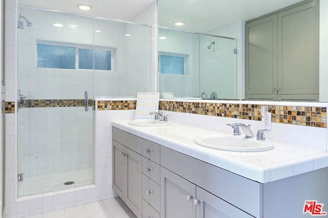 bathroom with decorative backsplash, tile patterned flooring, vanity, and a shower with door