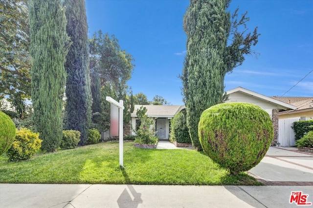 view of property hidden behind natural elements featuring a front yard