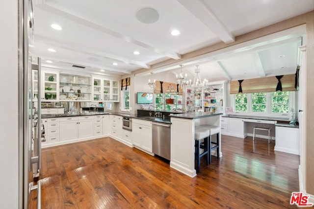 kitchen with stainless steel appliances, beamed ceiling, pendant lighting, a kitchen bar, and white cabinets