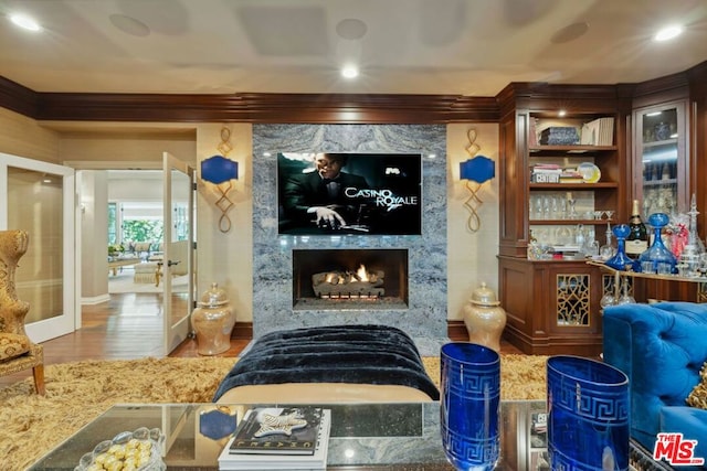 interior space featuring wood-type flooring, ornamental molding, and a premium fireplace