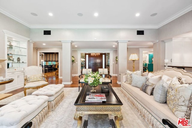 living room featuring light hardwood / wood-style floors, ornate columns, and crown molding