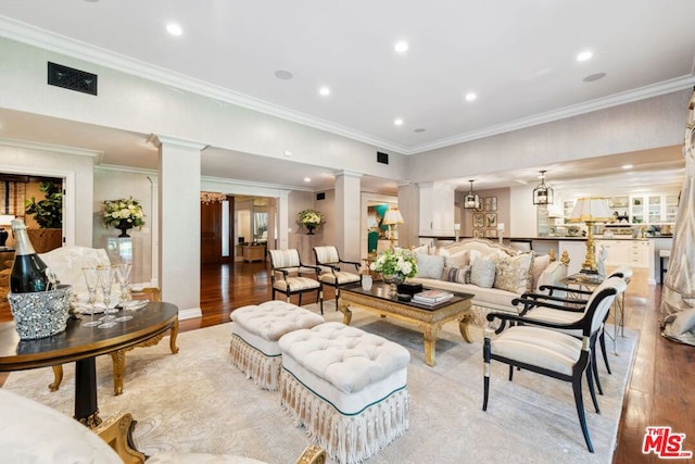 living room featuring light hardwood / wood-style floors, ornate columns, and ornamental molding