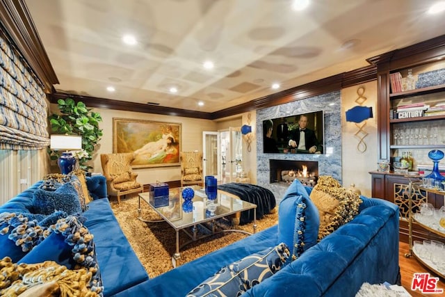 cinema room with crown molding, wood-type flooring, and a fireplace