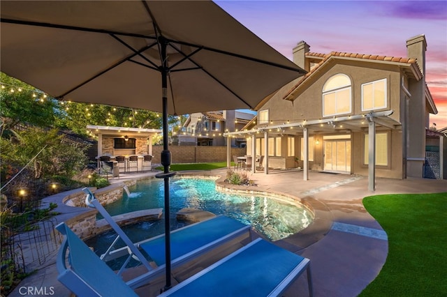 pool at dusk with a pergola, a bar, a patio area, pool water feature, and an in ground hot tub