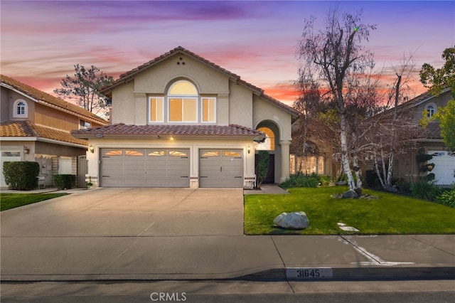 mediterranean / spanish home featuring a garage and a yard