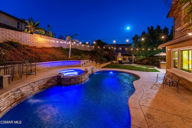 pool at twilight with pool water feature, a patio area, an in ground hot tub, and exterior fireplace