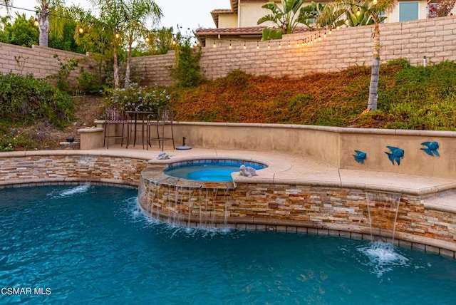 view of swimming pool with pool water feature and an in ground hot tub