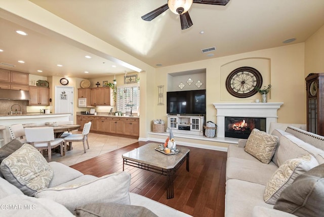 living room with ceiling fan, sink, and light wood-type flooring