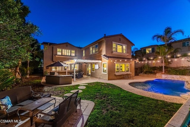 back house at night with outdoor lounge area, a fenced in pool, a pergola, and a patio