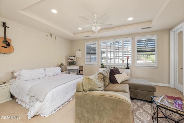 carpeted bedroom with a tray ceiling and ceiling fan