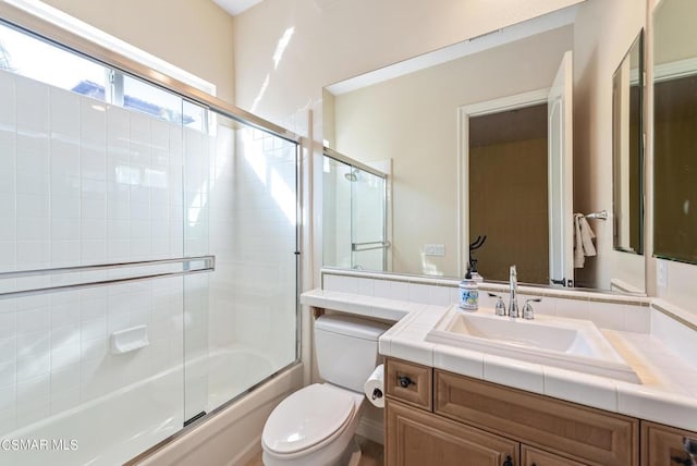 full bathroom featuring vanity, toilet, and combined bath / shower with glass door