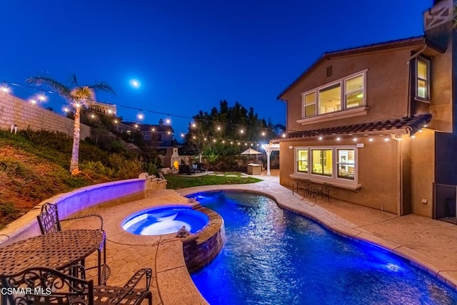 pool at twilight featuring a patio area and an in ground hot tub