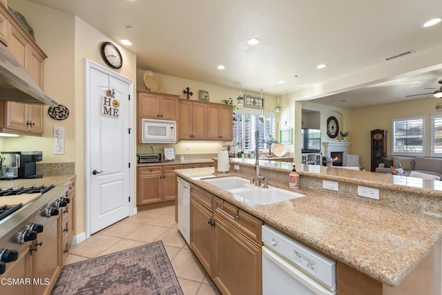 kitchen featuring a wealth of natural light, a center island with sink, white appliances, and sink