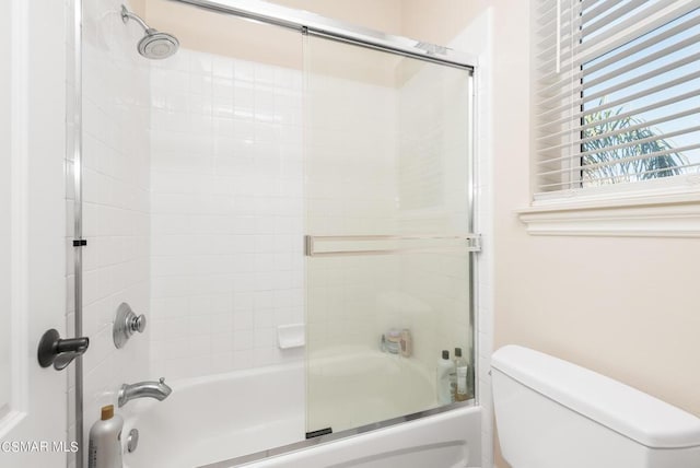 bathroom featuring enclosed tub / shower combo and toilet