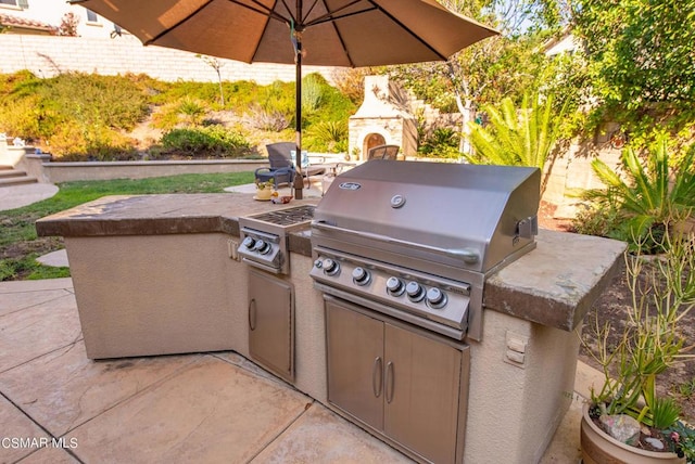 view of patio / terrace featuring a grill, exterior fireplace, and exterior kitchen