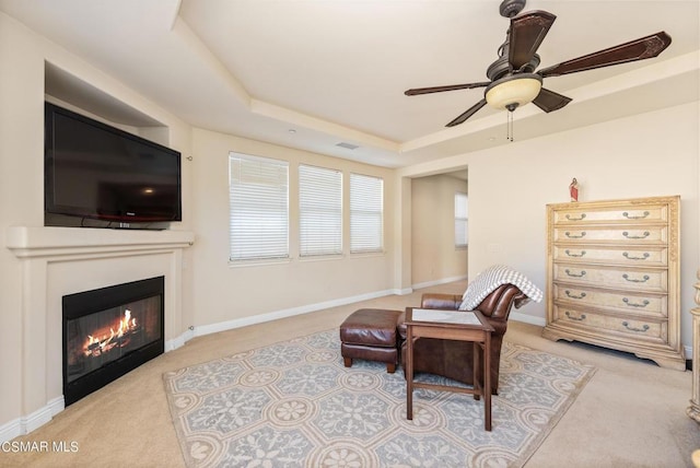 sitting room with a tray ceiling, ceiling fan, and light carpet