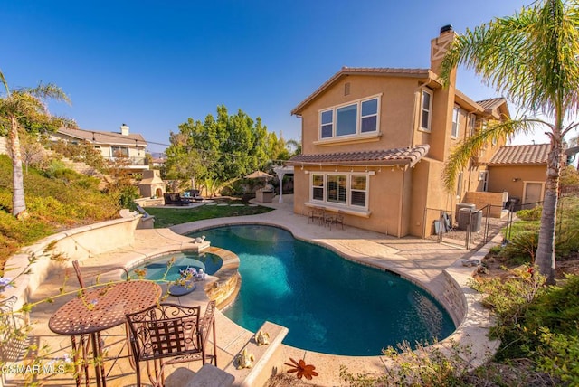 back of property with a patio area and a pool with hot tub