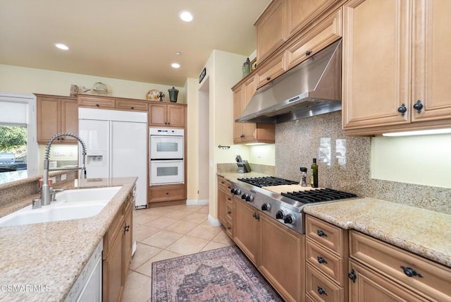 kitchen featuring light stone countertops, decorative backsplash, white appliances, sink, and light tile patterned floors