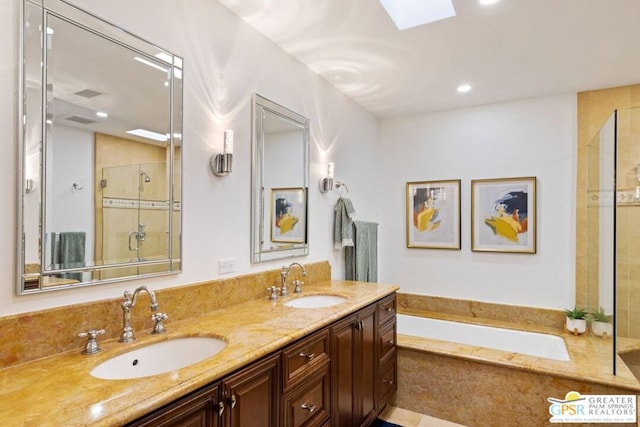 bathroom with a skylight, shower with separate bathtub, and vanity