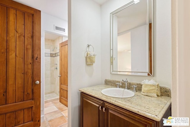 bathroom with tiled shower and vanity