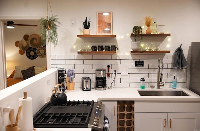 kitchen featuring white cabinets, tasteful backsplash, stainless steel gas range oven, and sink