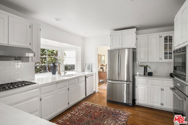 kitchen featuring sink, dark wood-type flooring, stainless steel appliances, backsplash, and white cabinets