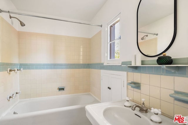 bathroom with sink, tile walls, tasteful backsplash, and tiled shower / bath