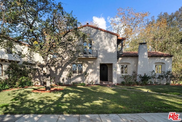 view of front of property featuring a balcony and a front lawn