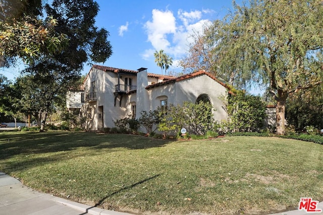 view of side of property with a balcony and a lawn