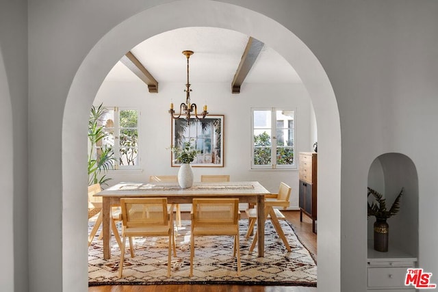 dining area featuring beamed ceiling, hardwood / wood-style flooring, and a chandelier