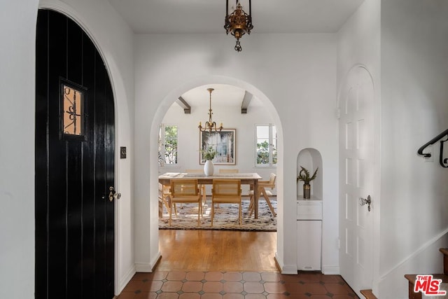 tiled foyer with a chandelier and beam ceiling