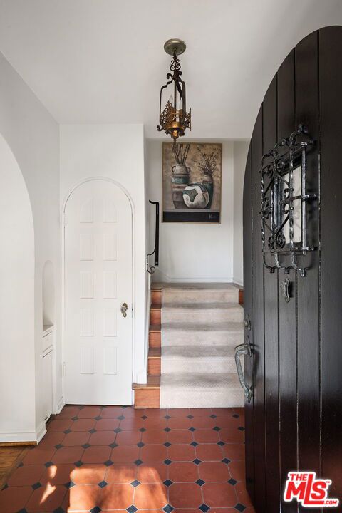 entryway featuring an inviting chandelier and dark tile patterned floors