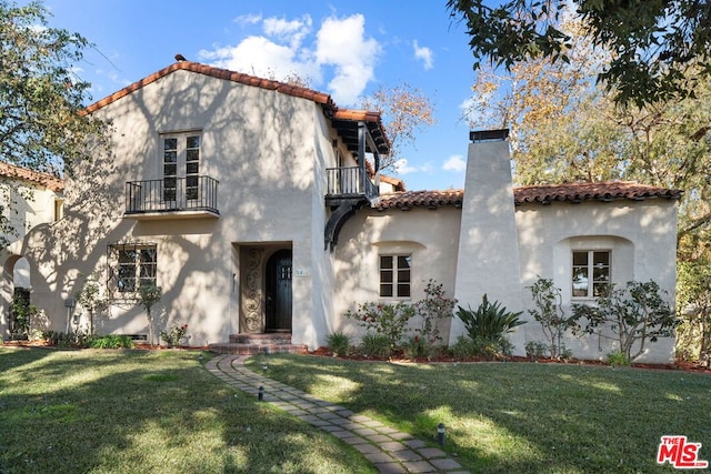 mediterranean / spanish house featuring a balcony and a front lawn