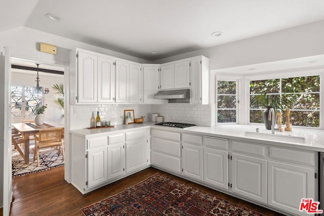 kitchen with backsplash, sink, dark hardwood / wood-style flooring, white cabinetry, and stainless steel gas cooktop