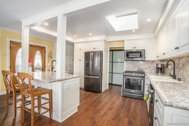 kitchen featuring sink, white cabinetry, a skylight, and appliances with stainless steel finishes