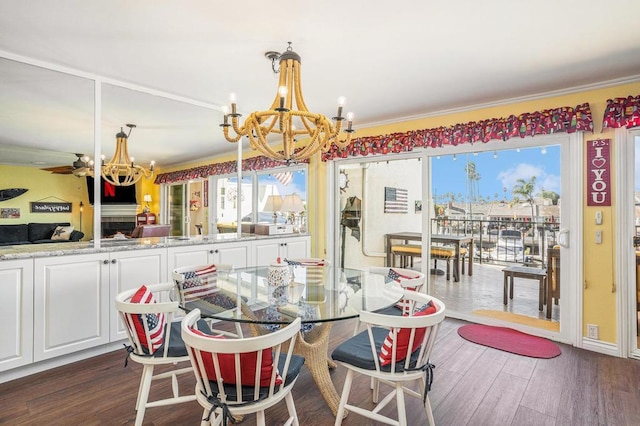 dining space with ceiling fan with notable chandelier, dark wood-type flooring, and ornamental molding