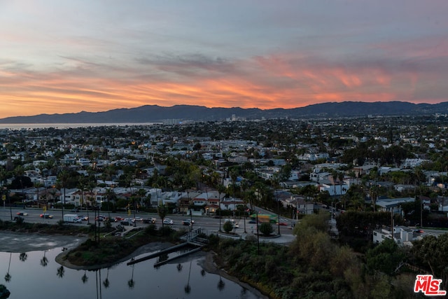 aerial view at dusk featuring a water and mountain view