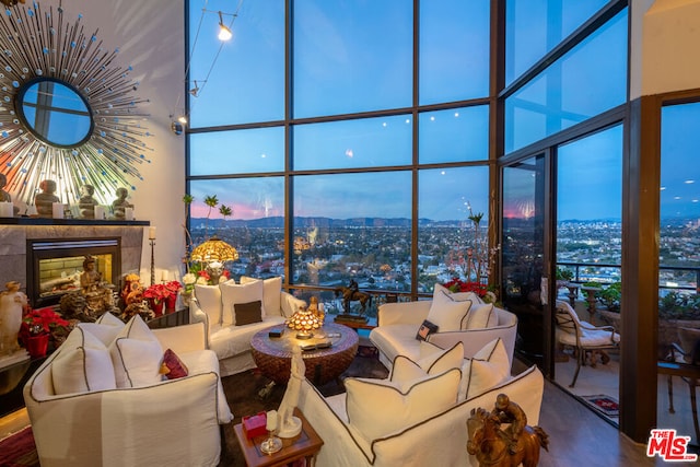 living room with a wealth of natural light, expansive windows, a fireplace, and a high ceiling