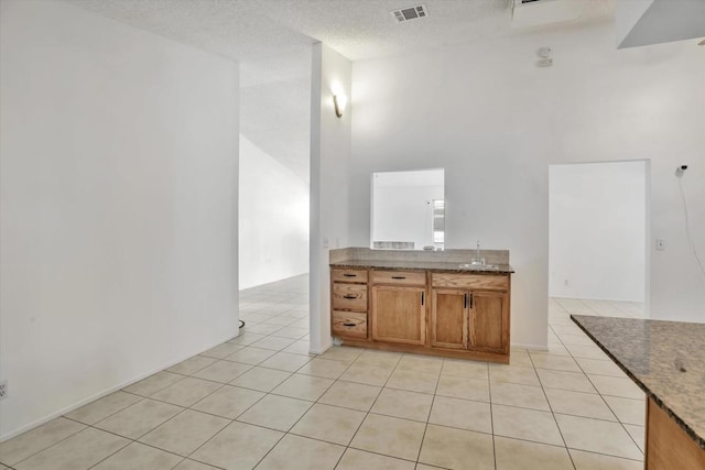 bathroom featuring sink, a high ceiling, tile patterned flooring, and a textured ceiling