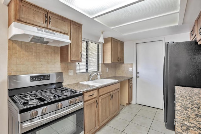 kitchen featuring light tile patterned floors, stainless steel gas range oven, sink, fridge, and backsplash