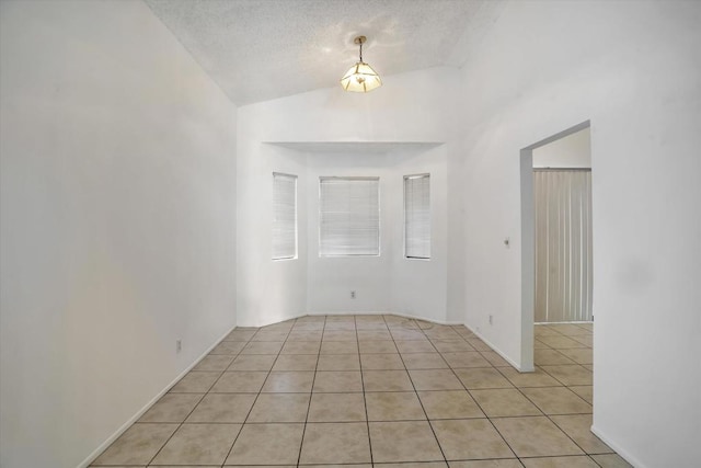 tiled empty room with lofted ceiling and a textured ceiling