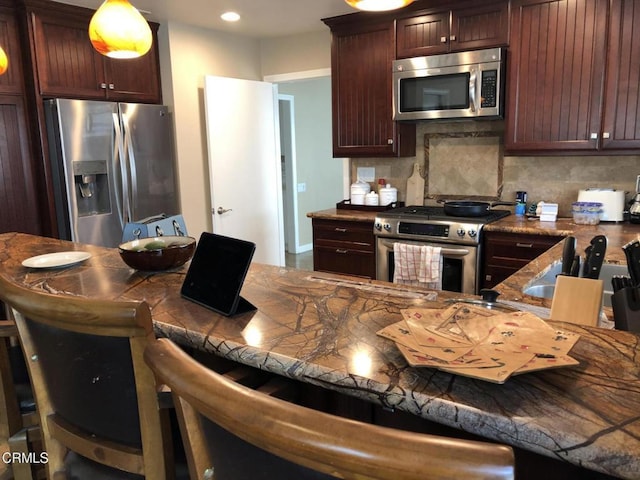 kitchen featuring decorative backsplash, pendant lighting, a breakfast bar, and stainless steel appliances