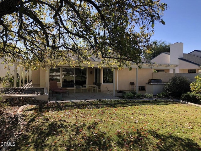 rear view of house featuring a lawn and a patio