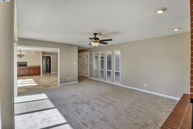 unfurnished living room with ceiling fan with notable chandelier and light colored carpet