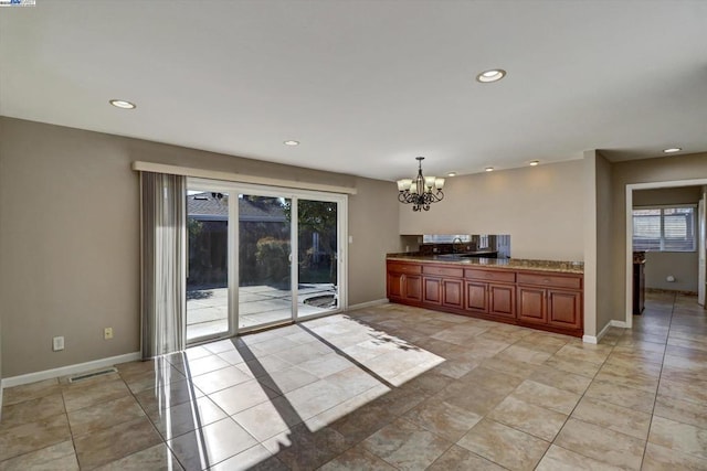 kitchen with a notable chandelier, light stone countertops, pendant lighting, and sink