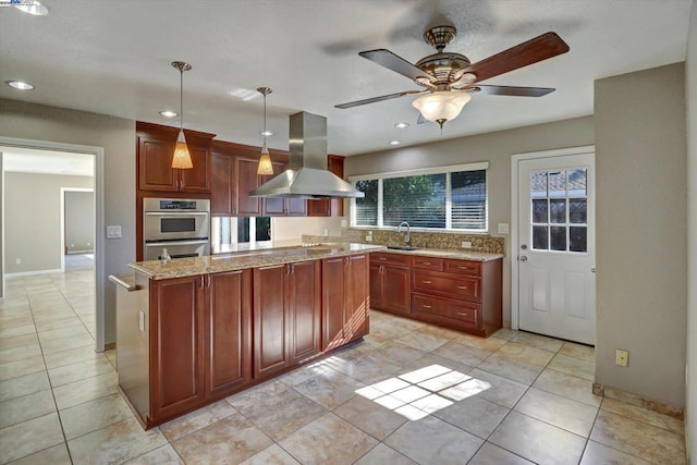 kitchen featuring pendant lighting, island exhaust hood, light stone counters, a kitchen island, and stainless steel double oven