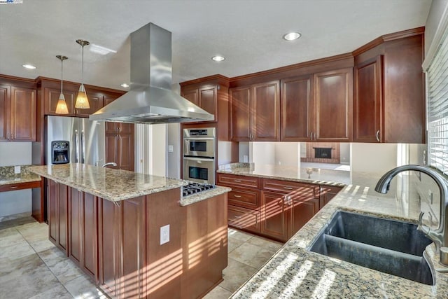 kitchen with appliances with stainless steel finishes, sink, decorative light fixtures, light stone countertops, and island range hood