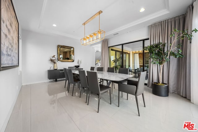 tiled dining area featuring ornamental molding and a tray ceiling