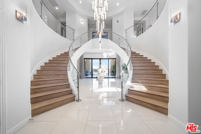 tiled entrance foyer featuring a high ceiling and a notable chandelier