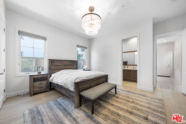 bedroom featuring light hardwood / wood-style floors, a notable chandelier, and ensuite bath